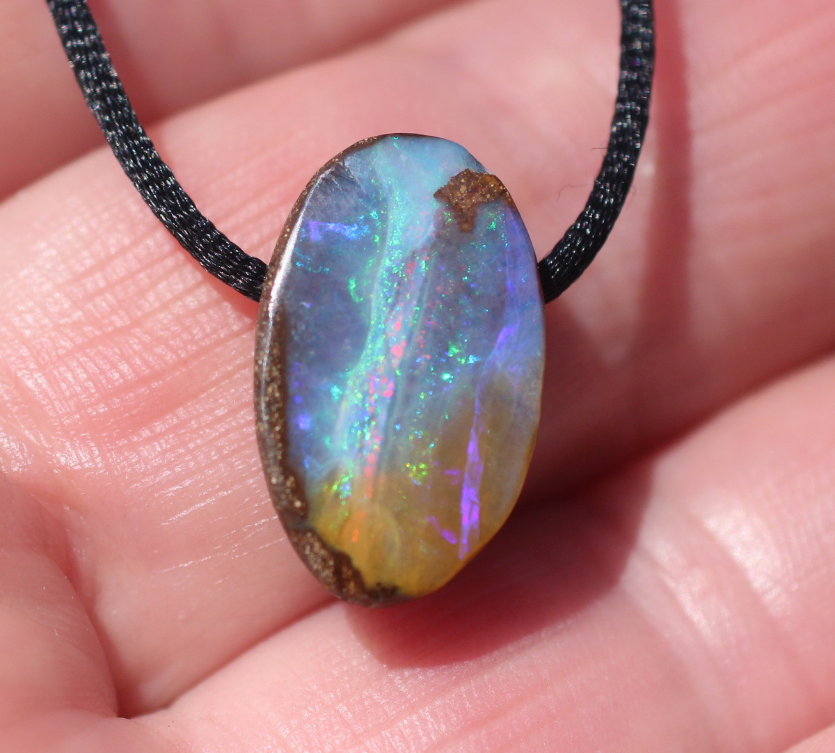 Kleiner ovaler Boulderopal, seitlich gebohrt mit Lederband 